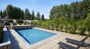 Piscine enterree dans un jardin avec terrasse et transats