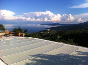 Piscine extérieure avec bâche à barres et vue sur la mer