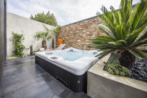 Spa portable sur une terrasse extérieure avec végétation et transats