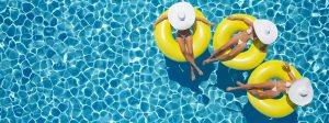 Piscine bleue avec trois bouées jaunes et femme se relaxant avec chapeau blanc