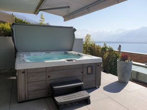 Spa portable sur une terrasse avec marchepieds et vue sur la mer