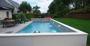 evidence-realisation-piscine-cascade Piscine enterree sur la terrasse d'une maison avec cascade d'eau dans le bassin