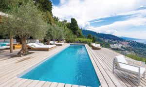 Piscine enterree sur terrasse en bois avec canapés pour se relaxer