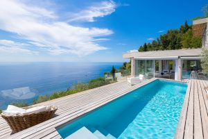Piscine enterree sur terrasse avec vue mer et canapes de jardin