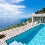 Piscine enterree sur terrasse avec vue mer et canapes de jardin