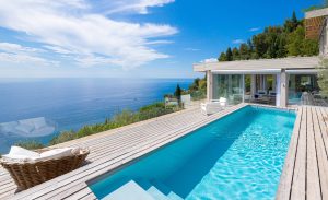 Piscine enterree sur terrasse avec vue mer et canapes de jardin