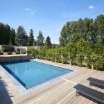 Piscine enterree avec terrasse en bois vegetation et transats