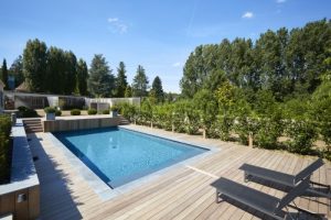 Piscine enterree avec terrasse en bois vegetation et transats
