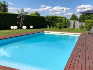 piscine enterree bleue dans un grand jardin avec terrasse en bois