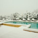 piscine et terrasse eneigée avec des transats sous la neige