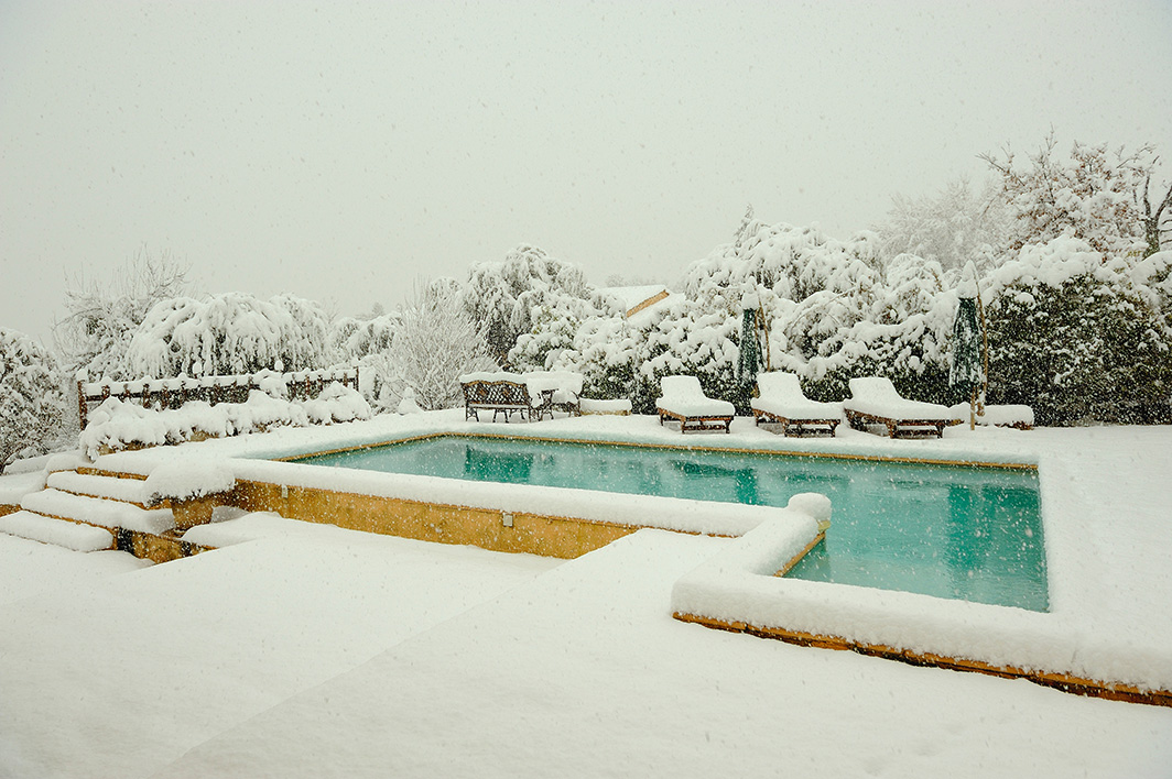 piscine et terrasse eneigée avec des transats sous la neige