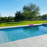 piscine enterree avec bouee rose dans un grand jardin