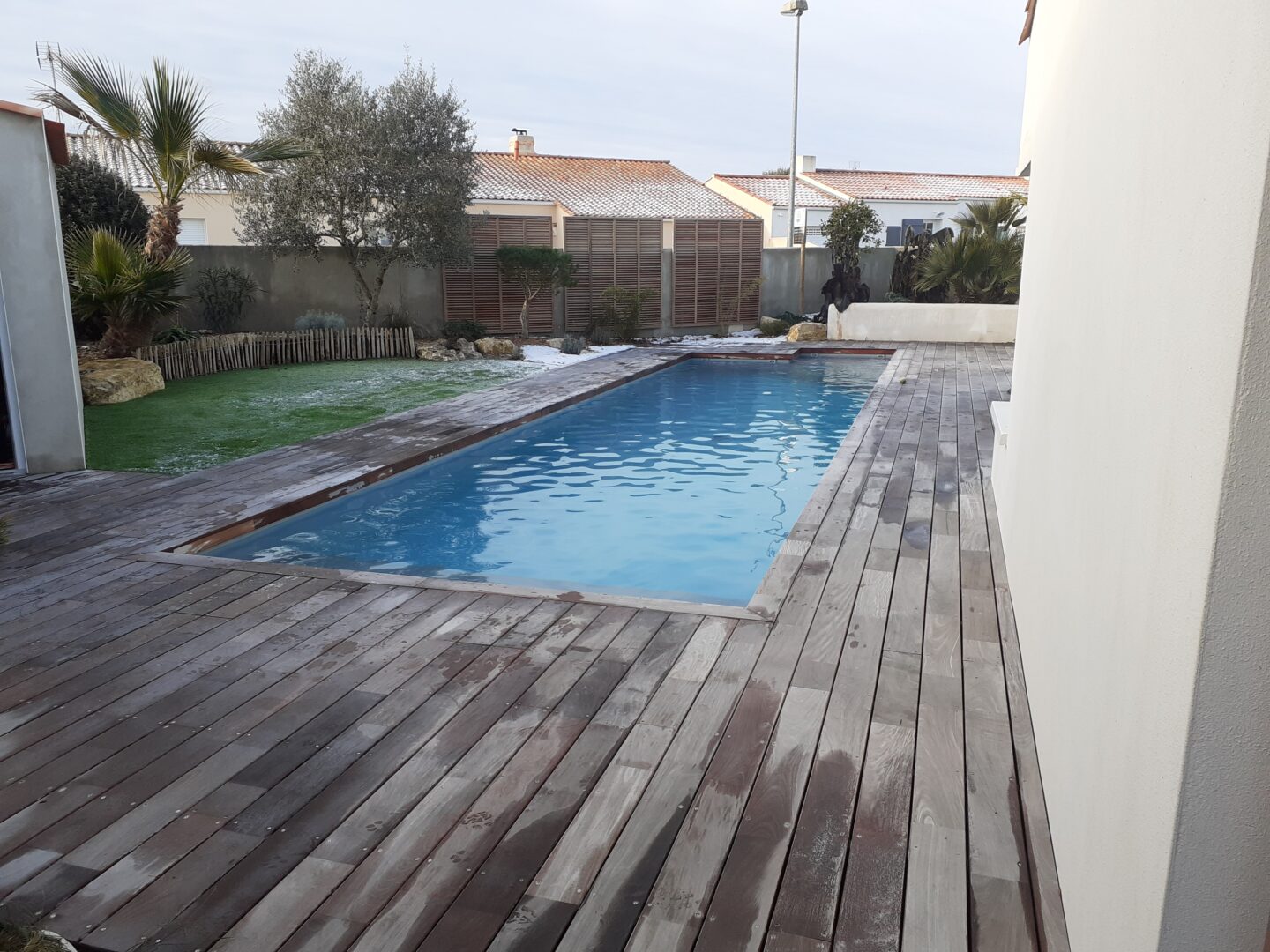 piscine enterrée avec terrasse en bois gris dans un jardin