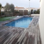 piscine enterrée avec terrasse en bois gris dans un jardin